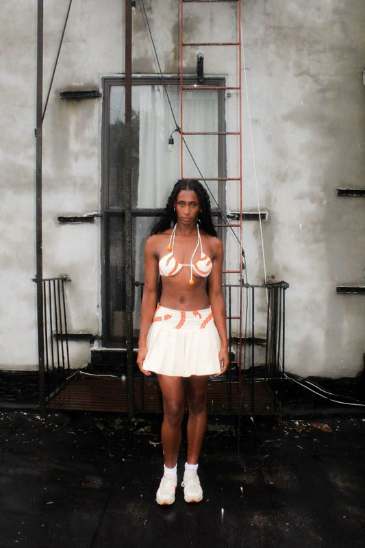 Lookbook image cream denim pleated mini skirt with orange velvet texture print and belt loops