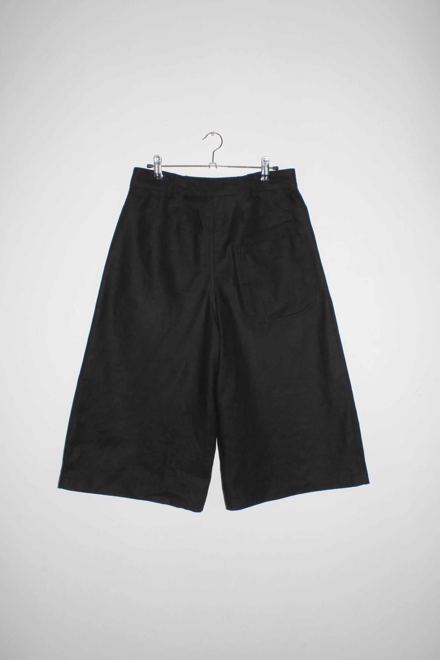 Back view lightweight long black denim shorts with removable screw buttons. Has fitted waist and 90s vintage details