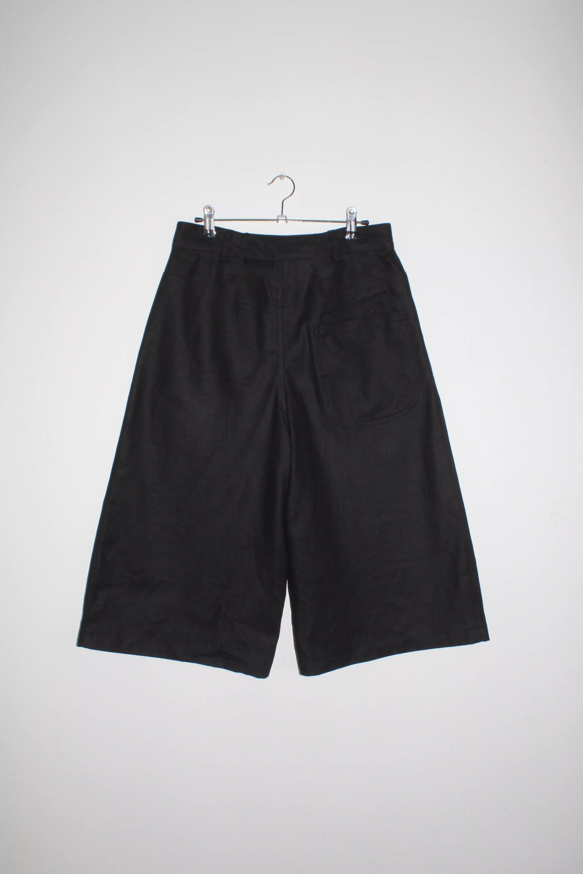 Back view lightweight long black denim shorts with removable screw buttons. Has fitted waist and 90s vintage details