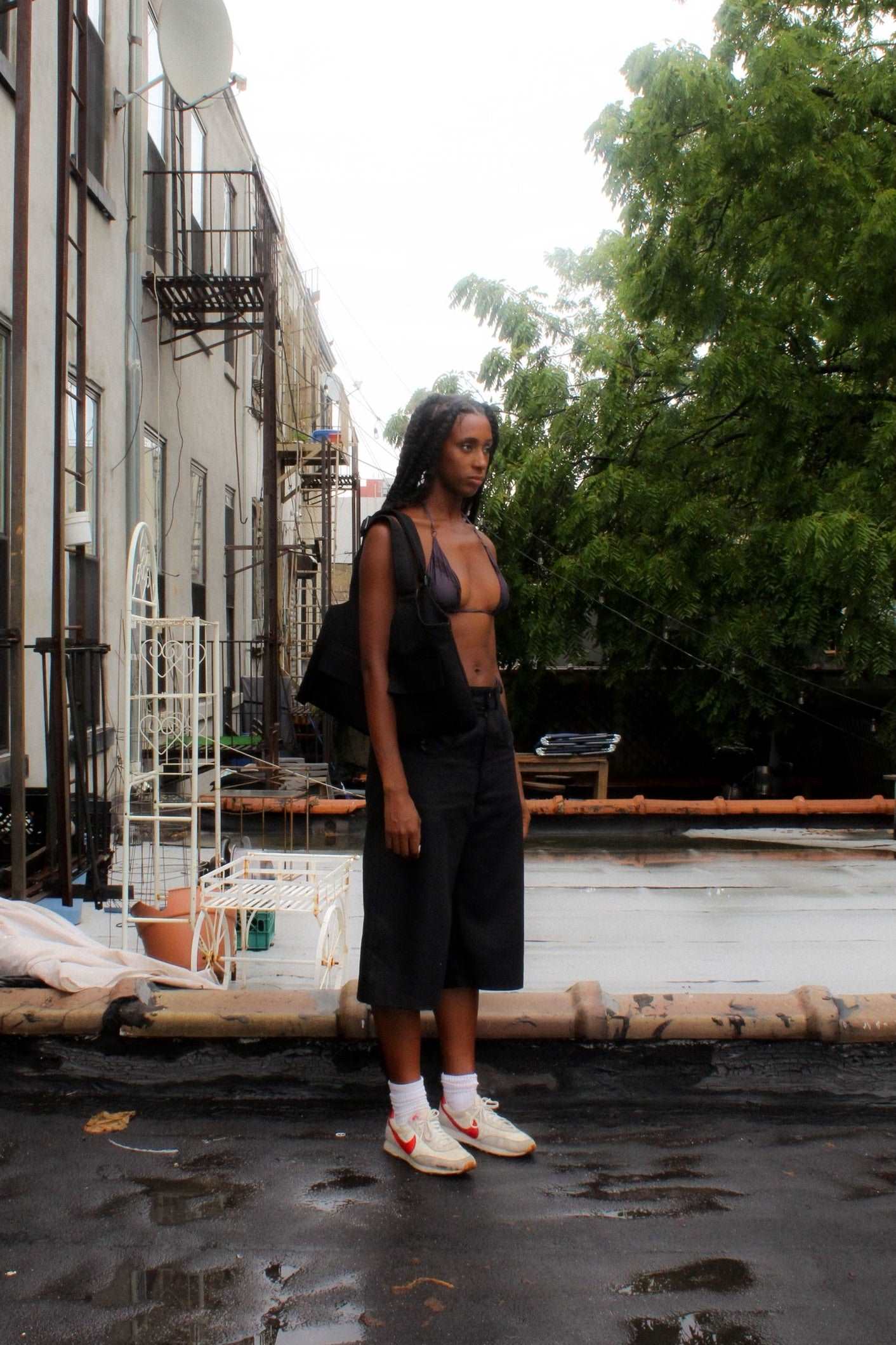 Lookbook image lightweight long black denim shorts with removable screw buttons. Has fitted waist and 90s vintage details