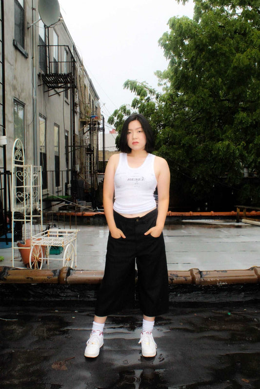 Lookbook image lightweight long black denim shorts with removable screw buttons. Has fitted waist and 90s vintage details