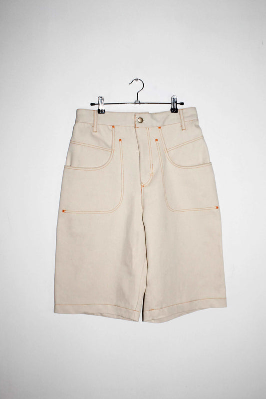 Front view cream shorts inspired by 90's vintage details. Featuring removable denim button, double pocket and Logo embroidery.