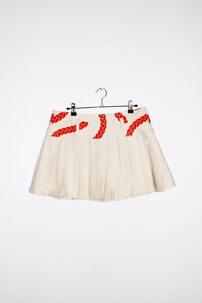Front view cream denim pleated mini skirt with orange velvet texture print and belt loops