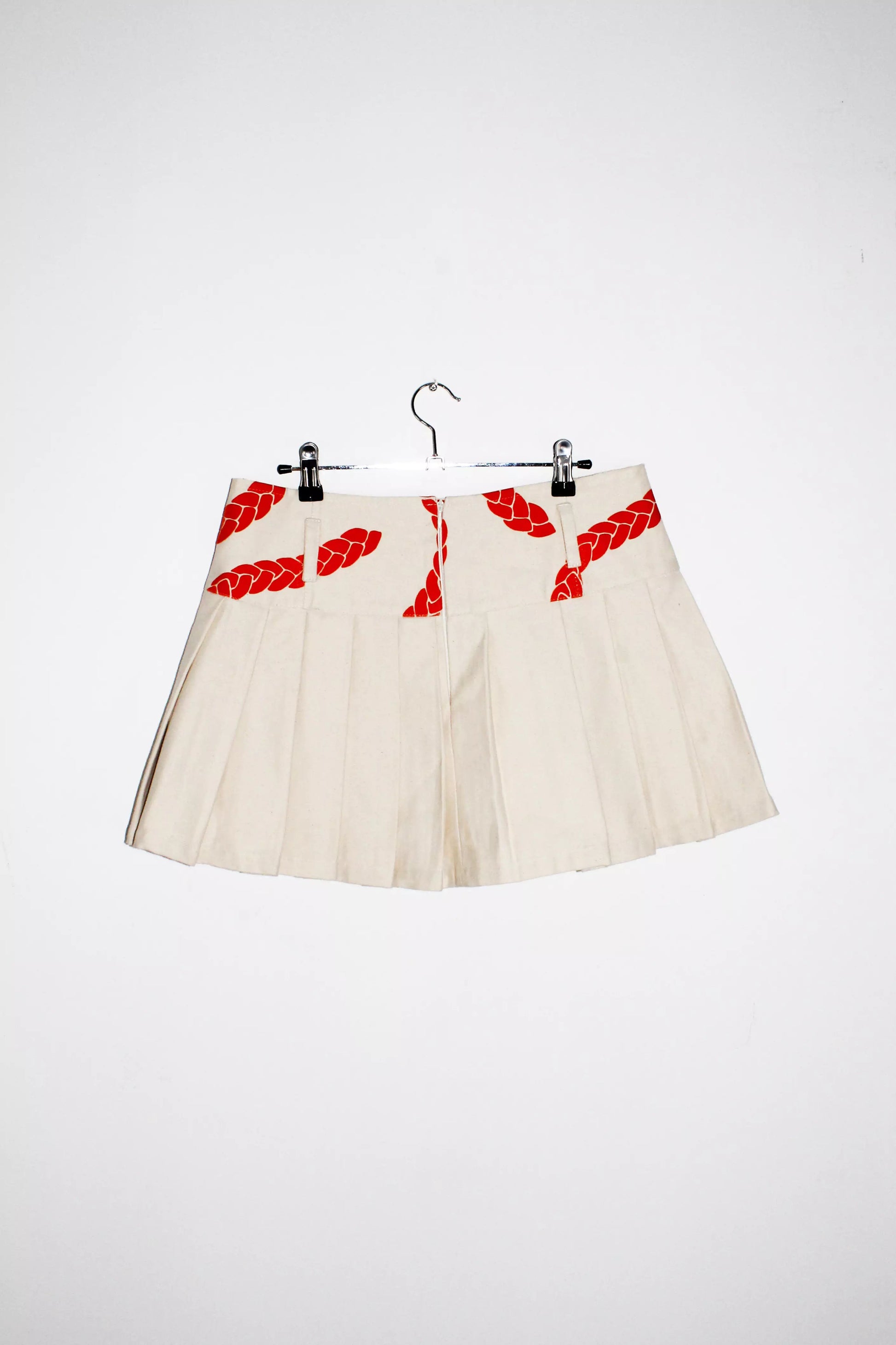 Back view cream denim pleated mini skirt with orange velvet texture print and belt loops