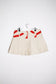 Back view cream denim pleated mini skirt with orange velvet texture print and belt loops
