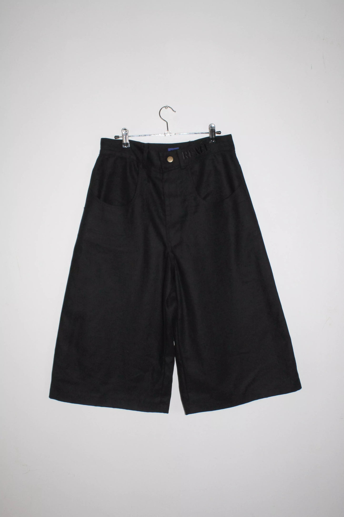 Front view lightweight long black denim shorts with removable screw buttons. Has fitted waist and 90s vintage details